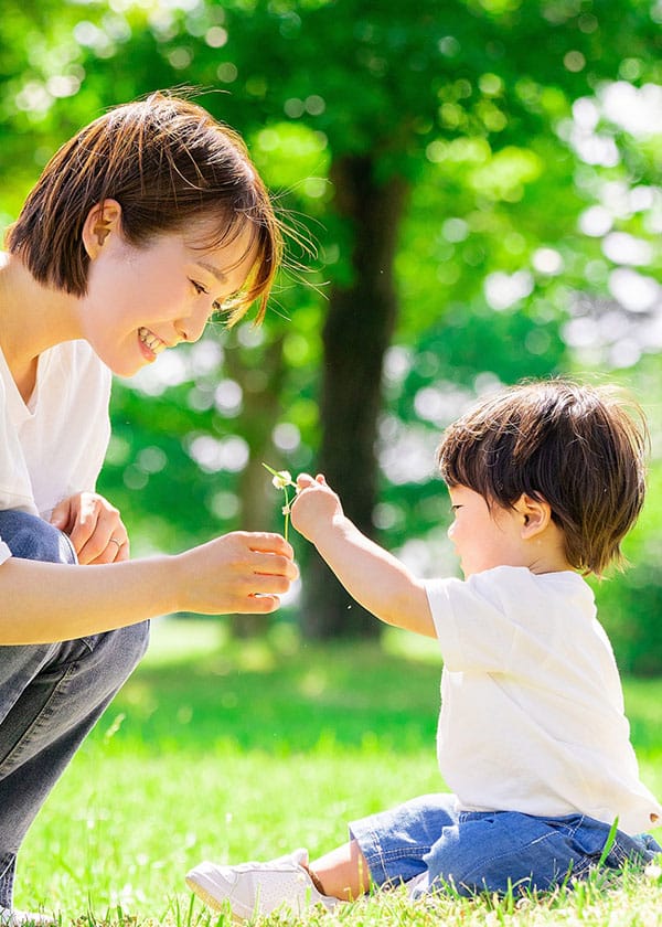 新緑の綺麗な公園で遊ぶ親子